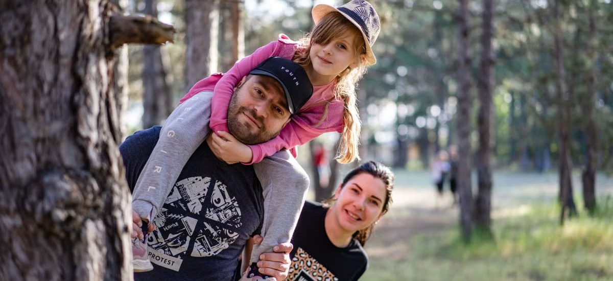 A joyful family enjoying a playful day in a sunlit forest park, capturing the essence of togetherness.